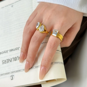 Detail of 18K gold plated rings with teardrop and emerald-cut cubic zirconia on a book
