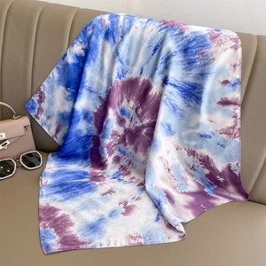 Detailed view of blue and purple gradient silk scarf styled on a premium leather sofa