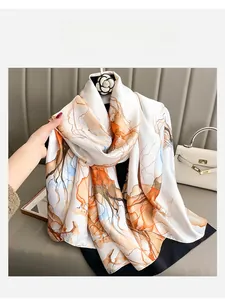 Detail of silk scarf with orange and brown abstract ink patterns held in hand