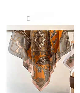 Détail d'un carré de soie bohème aux motifs cachemire dans les tons orange et marron