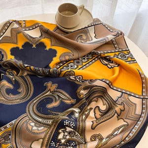 Détail d'un foulard en soie au motif cachemire avec fini satiné sur table de café