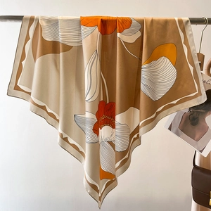 Large floral silk square scarf in khaki and orange draped on a minimalist hanger