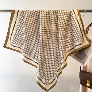 Close-up of vintage silk scarf featuring ivory monogram print and gold chain patterns