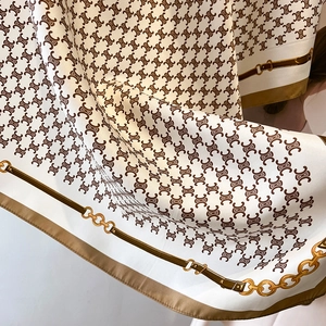 Macro detail of silky twill scarf showing classic monogram print and gold chain border