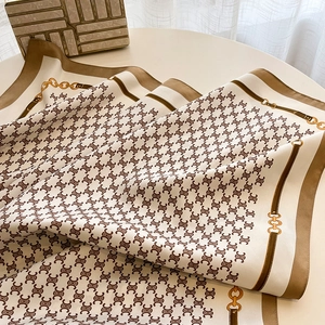 Detailed close-up of luxury silk scarf with elegant chain pattern and golden buckle accents