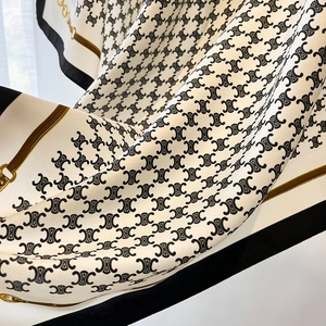 Detail of elegant ivory silk scarf featuring black chain borders and classic gold patterns