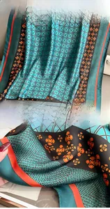 Detail of silk-like scarf with geometric patterns, floral prints and fine edge stitching