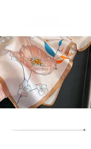 Détail des bords roulottés et de la texture de la soie avec motifs floraux du foulard