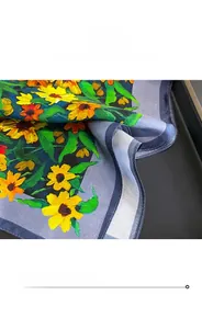 Detail of sunflower silk scarf showing the fine stitching and finished edge on blue fabric