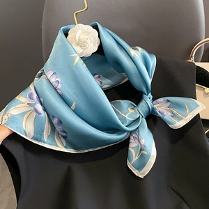 Elegante foulard di seta celeste con stampa floreale viola annodato su un colletto