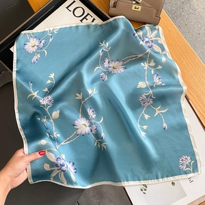 Foulard di seta blu lago con stampa floreale e bordi bianchi su tavolo in legno