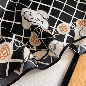 Elegant silk camellia scarf with black grid patterns and orange floral accents