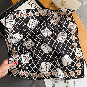 Premium black and white silk camellia square scarf displayed on a wooden table