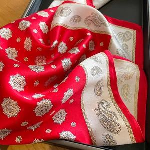 Foulard en soie avec motif paisley rouge et crème, présenté dans un coffret cadeau chic