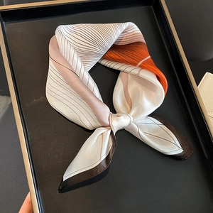 Silk neckerchief with geometric patterns in pink and orange on a black tray display