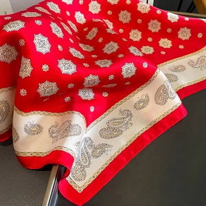 Détail d'un foulard en soie rouge avec motif cachemire sur fond de cuir sombre