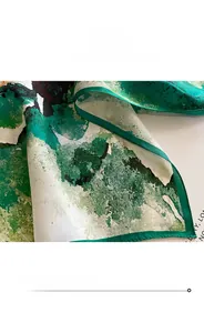 Macro shot of high-quality silk scarf edge with fine green stitching and artistic print