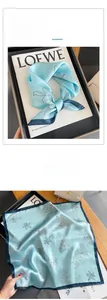 Detailed macro view of mint silk scarf with white floral prints and navy rolled edges
