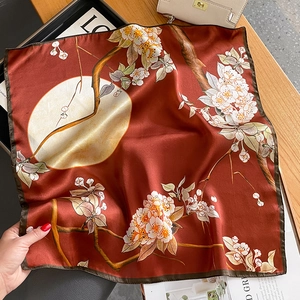 Detail of silk square scarf featuring elegant floral patterns and hand-rolled edges