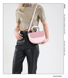 Pink saddle bag featuring large silver metal handle and glossy faux leather texture