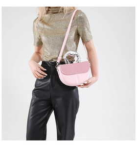 Detailed view of pink saddle bag with silver textured metal handle and adjustable strap