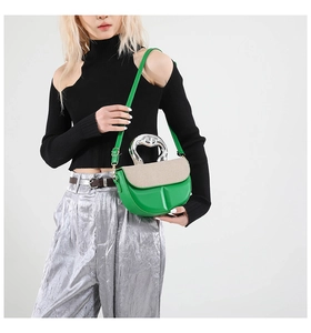 Close-up of green leather handbag featuring a woven flap and metallic T-shaped handle