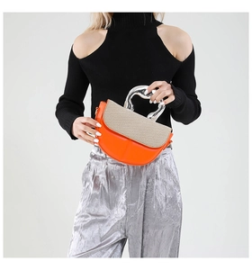 Detail of orange leather and beige woven saddle bag with a silver metallic handle