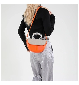 Detail of orange saddle bag with silver metallic handle and snake skin texture flap