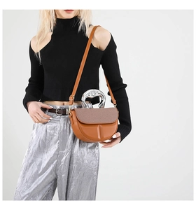 Detailed side view of the brown leather shoulder bag with a unique silver metal handle