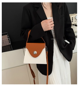 Détail d'un sac à main bicolore pour femme avec texture plissée et boucle ronde en métal