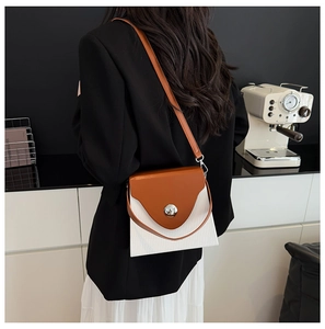 Détail du sac boîte bicolore avec boucle magnétique argentée sur surface texturée blanche