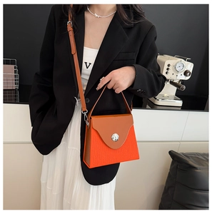 Détail du sac bandoulière plissé orange avec rabat marron et boucle en métal argenté