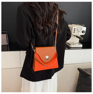 Détail du sac à bandoulière bicolore orange et marron avec fermoir métallique argenté