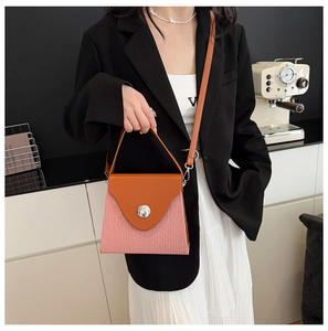 Détail du sac boîte bicolore avec rabat orange et corps rose à texture gaufrée ondulée