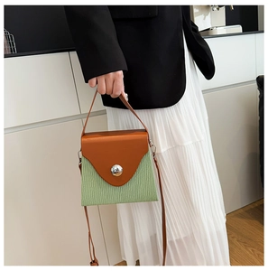 Détail du sac bandoulière avec texture plissée verte et rabat en cuir marron