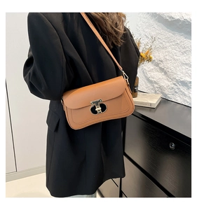 Détail d'un sac vintage en cuir marron avec une boucle en T dorée et une bandoulière