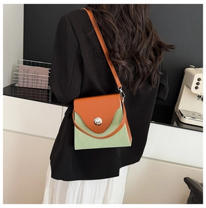 Détail du sac bandoulière bicolore en cuir orange et texture plissée vert clair moderne