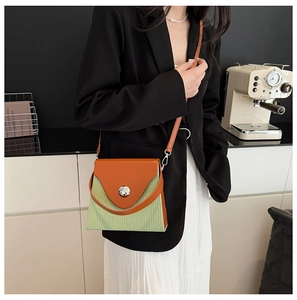 Détail du sac boîte tendance avec empiècement en cuir contrasté et fermoir rond argent