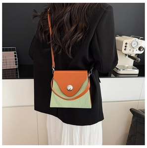 Détail du sac boîte moderne orange et vert avec boucle argentée porté par un mannequin