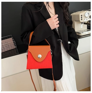 Détail du sac boîte rouge plissé avec rabat orange et boucle en métal argenté