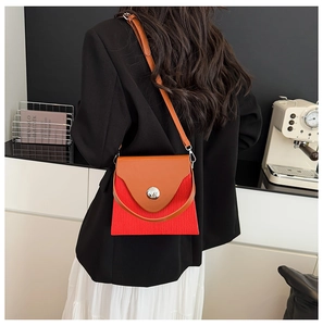 Détail d'un sac à main en tissu rouge texturé avec rabat en cuir dans un décor moderne