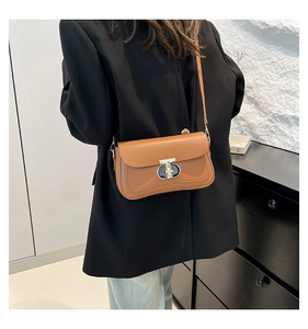 Sac bandoulière en cuir marron avec boucle en T porté sur un mannequin en costume