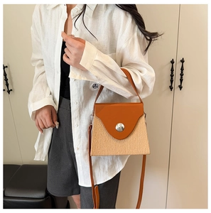 Détail du sac de couleur contrastée avec poignées en cuir marron et texture tissée