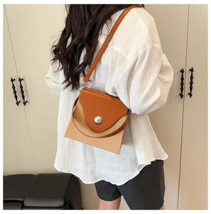 Détail d'un sac bandoulière bicolore chic avec texture paille et rabat en cuir