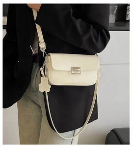 Detail of cream white leather shoulder bag featuring silver rectangular lock and flower charm