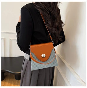Détail du sac à bandoulière plissé gris avec rabat en cuir orange et boucle argentée