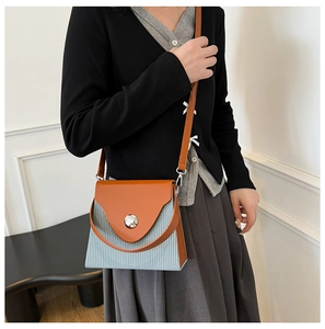 Détail du sac bandoulière bicolore avec rabat orange et corps bleu à texture