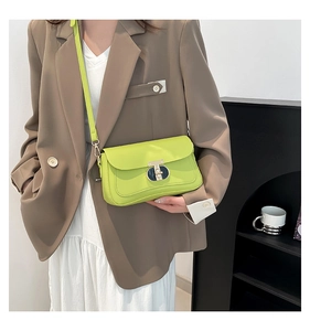 Détail du sac bandoulière vert fluo avec fermoir en métal porté sur un blazer brun