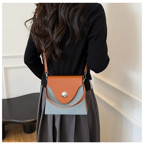 Détail du sac boîte bicolore avec rabat en cuir orange et texture rayée bleue