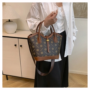Detail of vintage handbag with clover print, caramel stitching and golden metal clasp